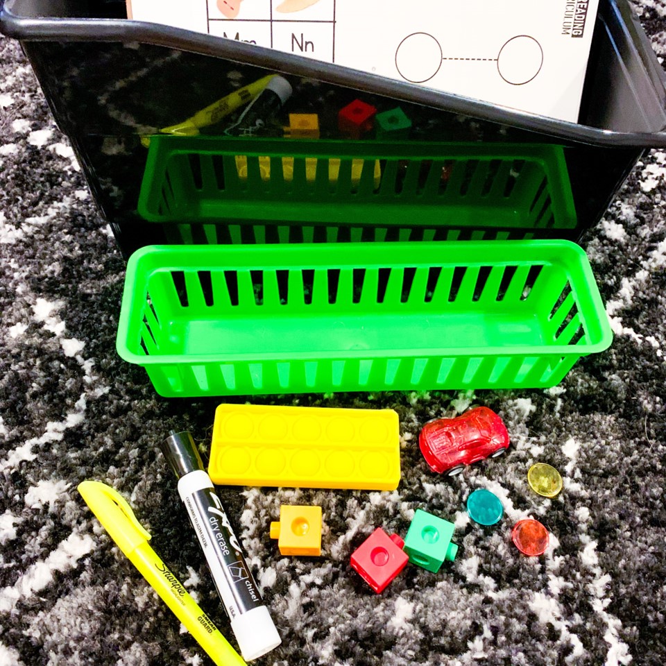 Kindergarten guided reading small group student supplies showing a pencil tray with highlighter, dry eraser marker, ten frame pop it, toy car, cubes, and counters