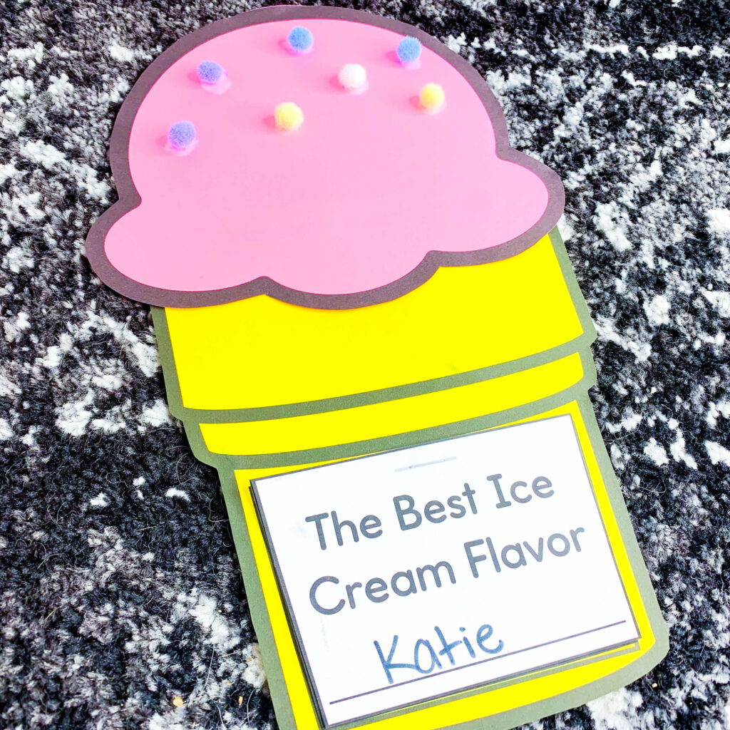 free end of the year ice cream theme days for kindergarten and first grade | image shows an ice cream writing craft on a black and white carpet. The craft shows a pink scoop with pom-pom sprinkles, a yellow cone, and the words "The best ice cream flavor"
