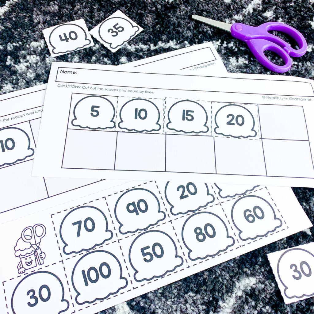 free end of the year ice cream theme days for kindergarten and first grade | image shows an ice-cream themed skip counting math worksheet and scissors on a black and white carpet