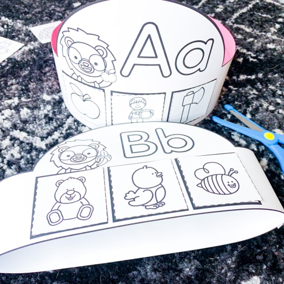 free alphabet crowns or hats with Letter Lion | image shows a letter Aa hat standing up and a letter Bb hat laying down on a black and white carpet